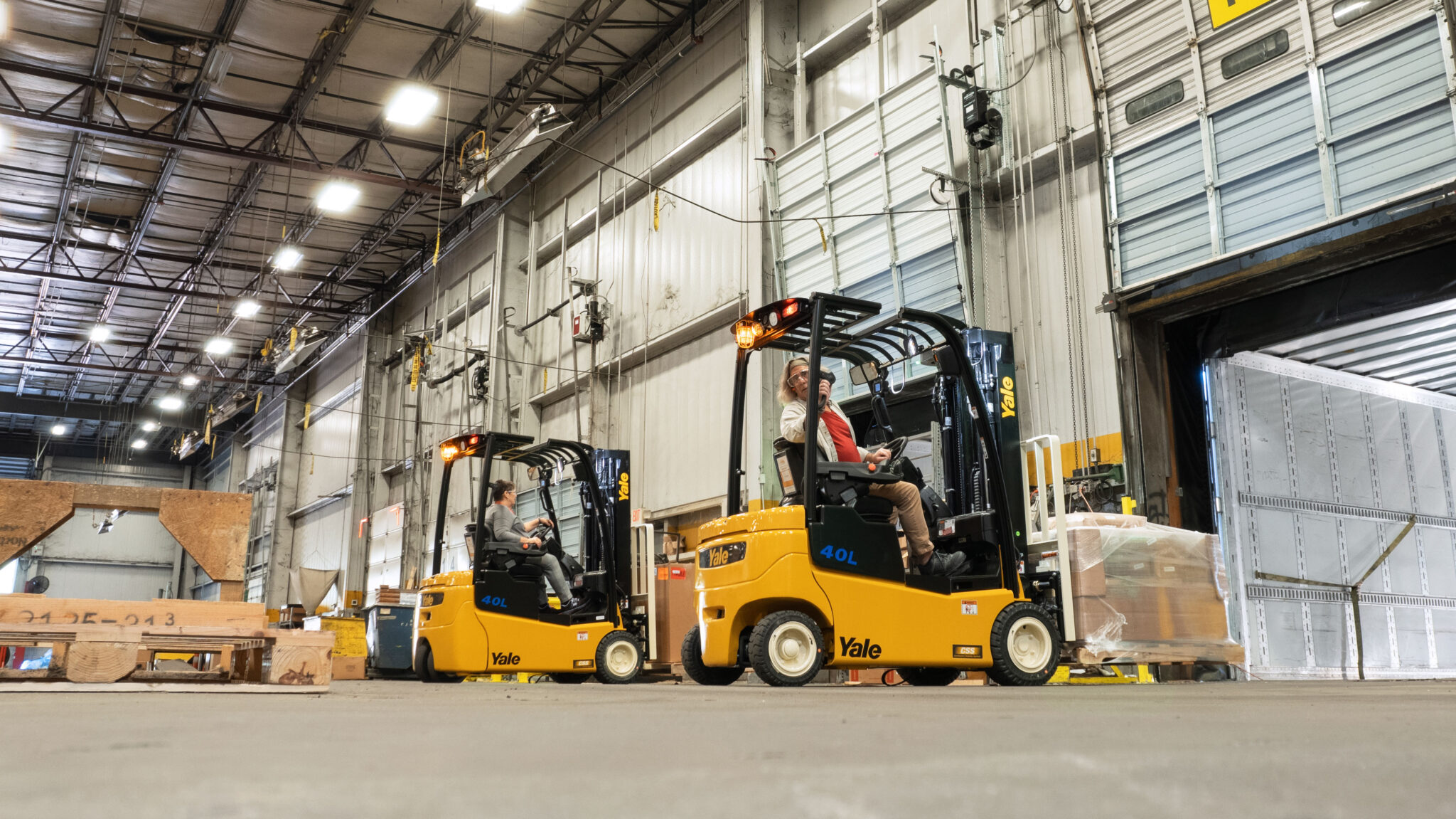 Two warehouse employees driving Yale forklifts.